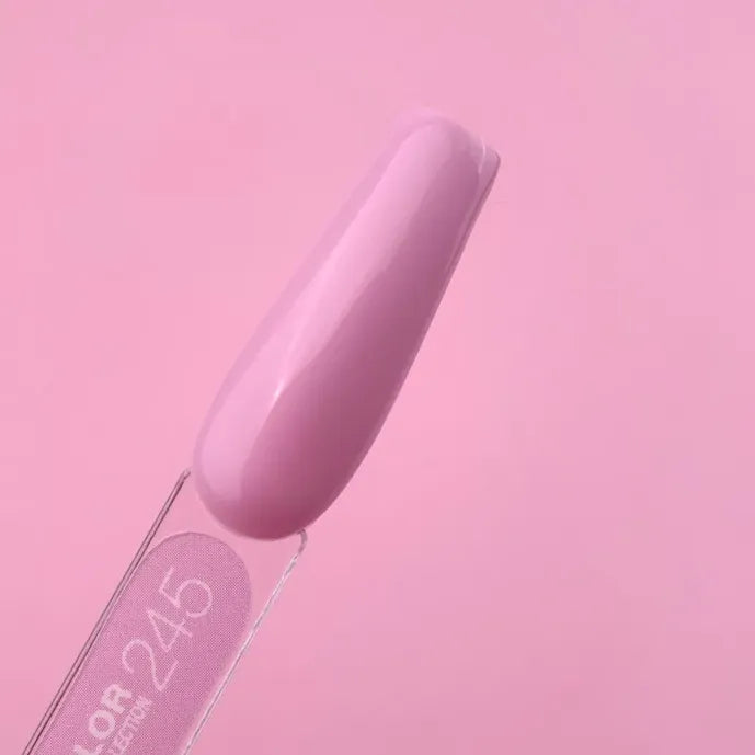 Swatch of glossy light pink gel nail polish on a sample stick against pink background