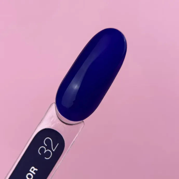 Glossy dark blue gel nail polish color sample on display stick, pink background.