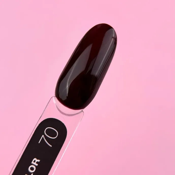 Dark burgundy gel nail polish swatch on display stick with pink background