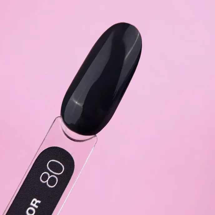 Glossy black nail gel polish swatch on stick against pink background