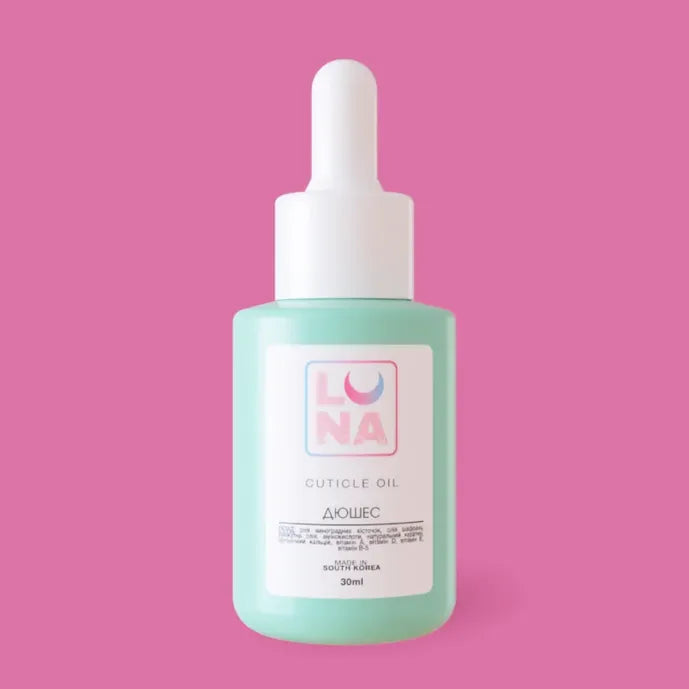 LUNA cuticle oil in a light blue dropper bottle for nail and cuticle care on a pink background.
