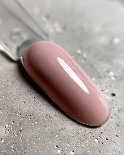 Swatch of glossy nude pink gel nail polish on display stick for manicure