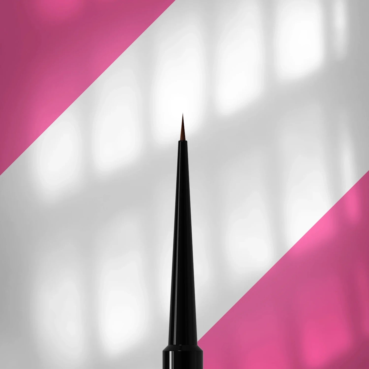 Fine nail art brush with black handle on pink and white diagonal background, manicure tool