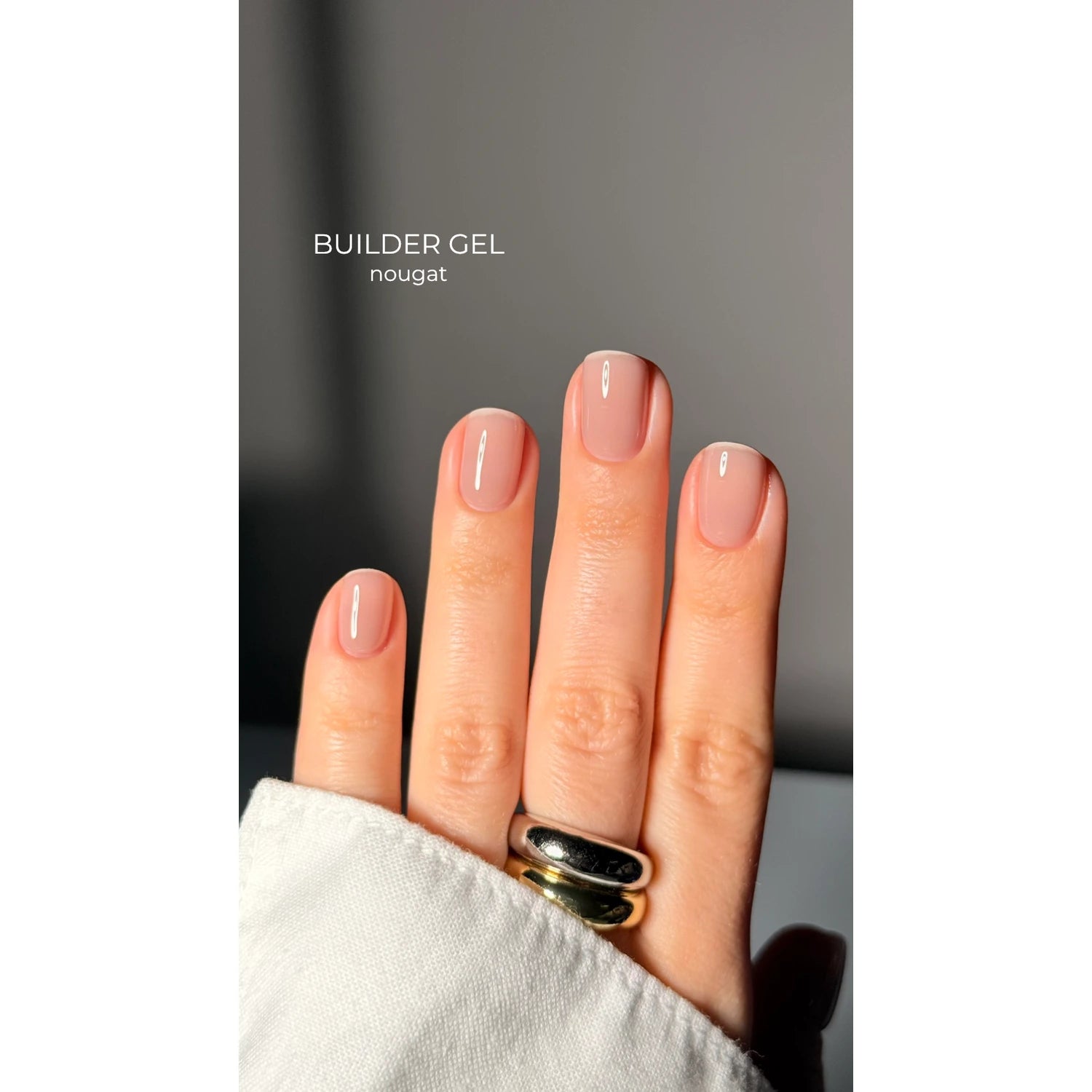 Hand with short, natural nails featuring nude pink builder gel in nougat shade