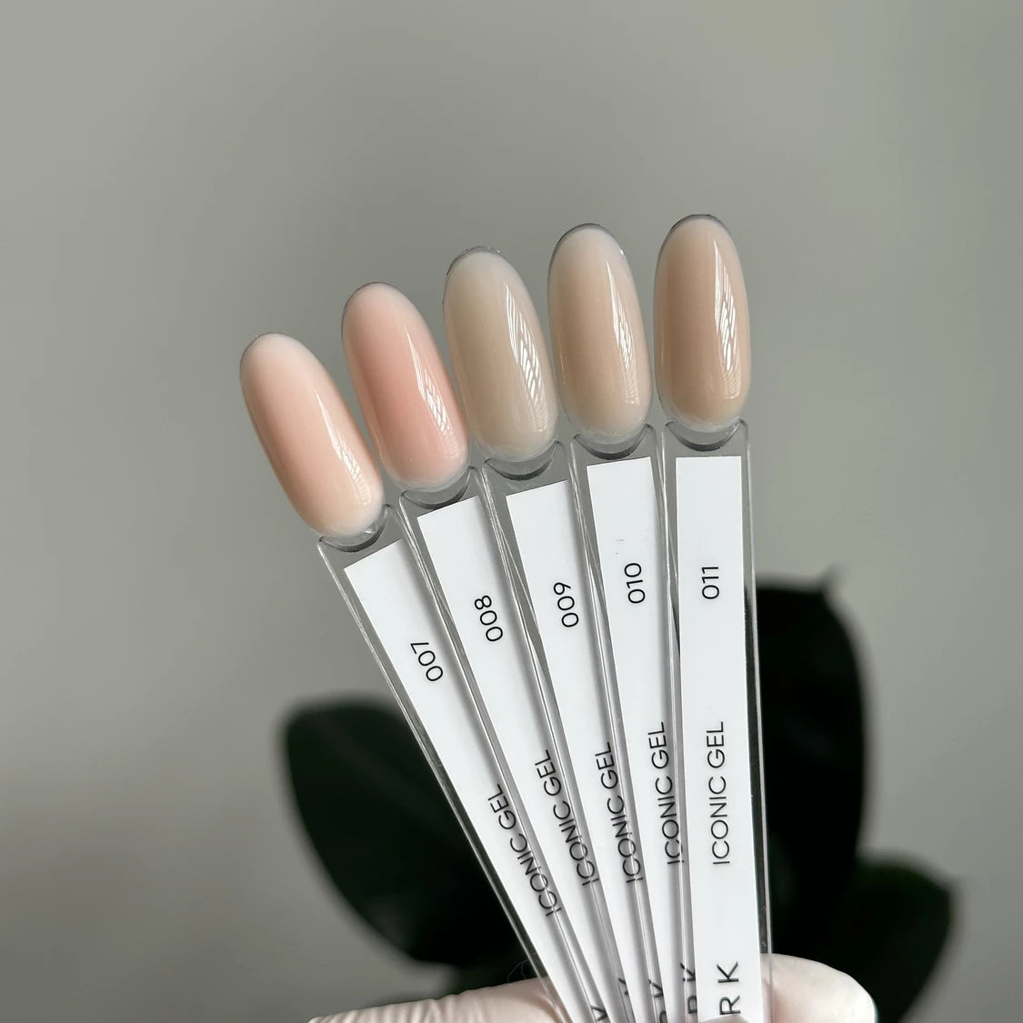 Five neutral nude gel nail polish swatches on display sticks for manicure