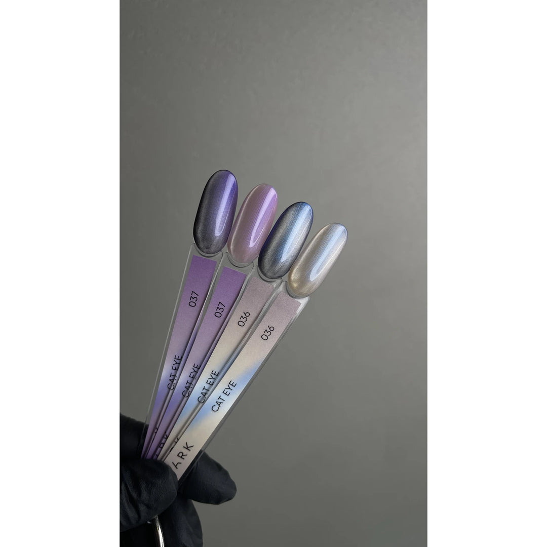 Four cat eye gel nail polish sample sticks in metallic purple and silver shades, held by a gloved hand