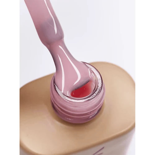 Close-up of pink builder gel for nails in an open bottle with brush applicator