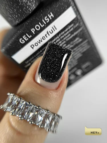 Black glittery nail polish on a finger with a 'Gel Polish Powerfull' box in the background.