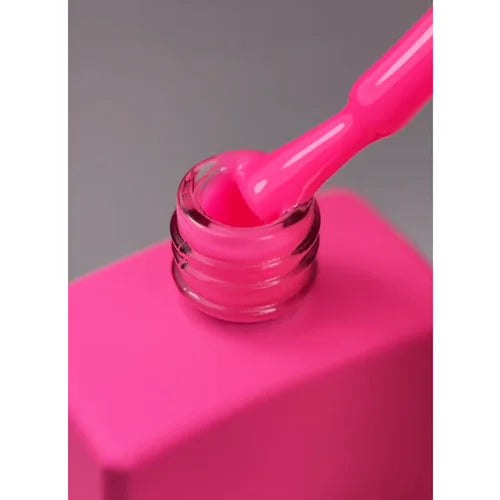 Bright pink nail gel polish in open bottle with applicator brush, close-up.