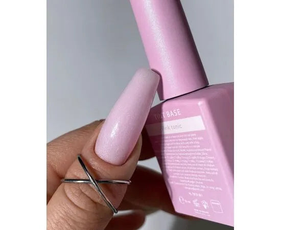 Hand with long light pink gel polished nail holding matching pink nail polish bottle