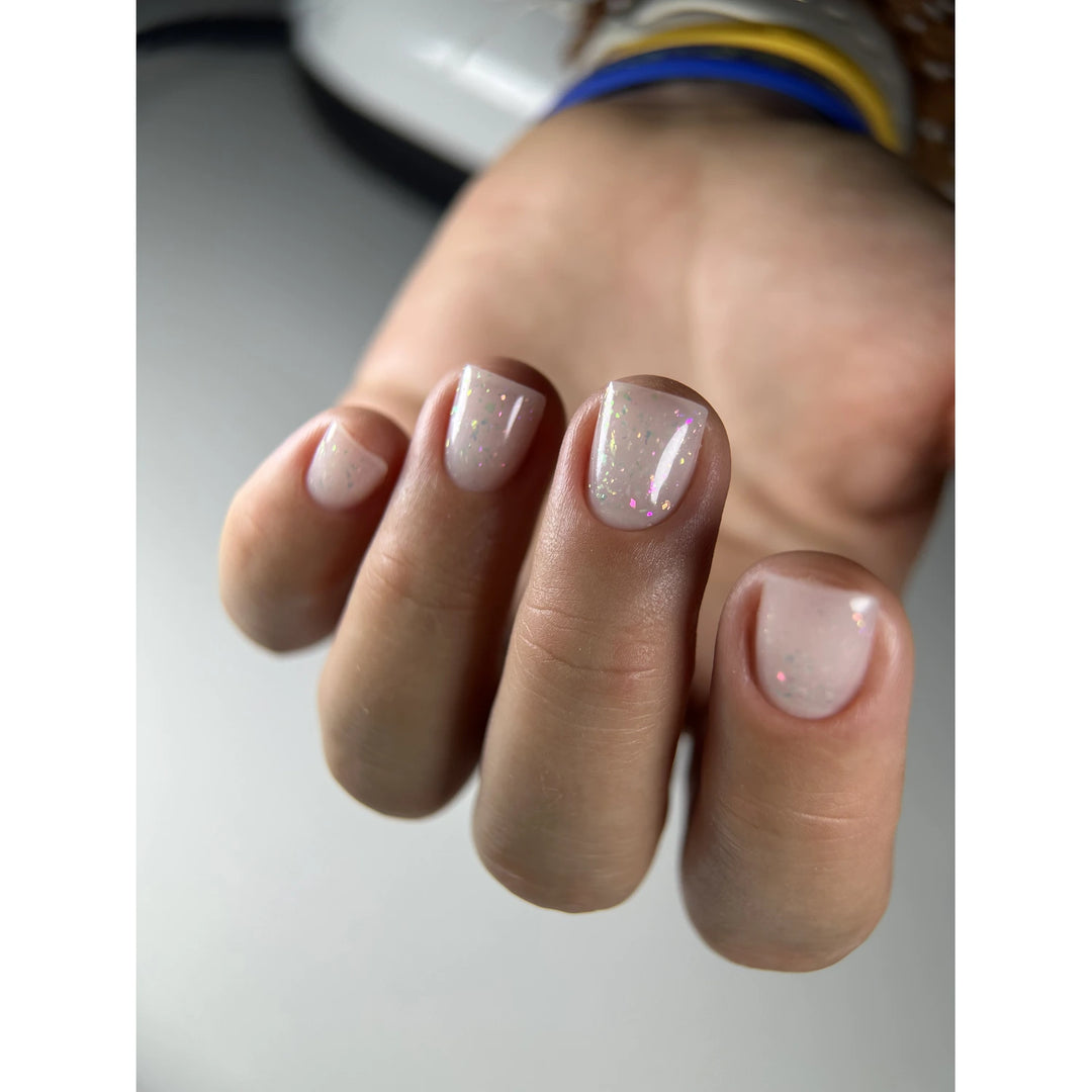 Hand with short nails featuring sheer pink gel polish and subtle iridescent glitter
