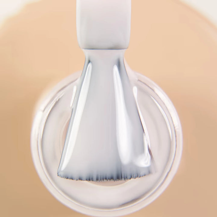 Close-up of nail polish brush with nude beige gel polish for manicure