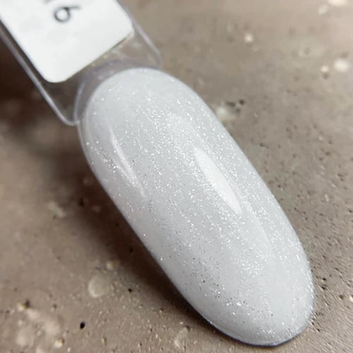 Shimmery white UV gel nail polish swatch on a sample tip, shown on textured surface