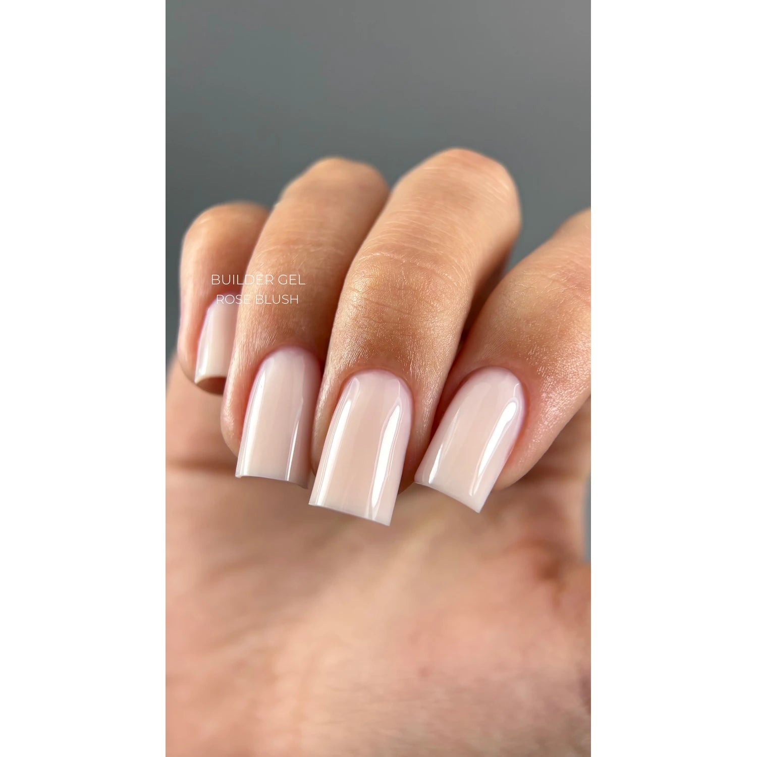 Hand with square-shaped nails featuring glossy rose blush builder gel manicure