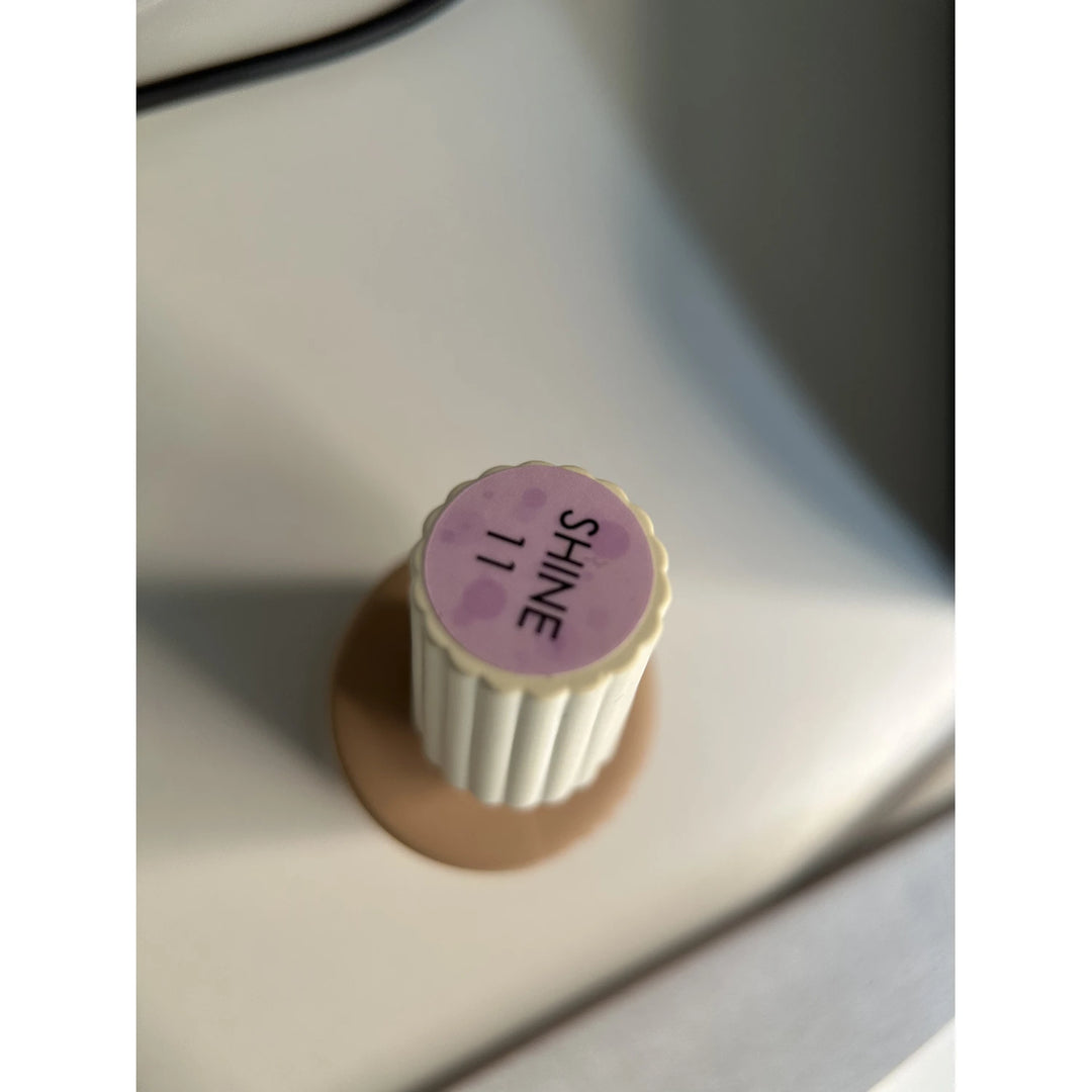 Nail polish bottle top labeled SHINE 11, pale pink cap, manicure accessory