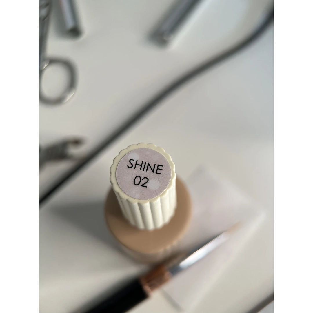 SHINE 02 gel nail polish bottle with manicure tools on white background