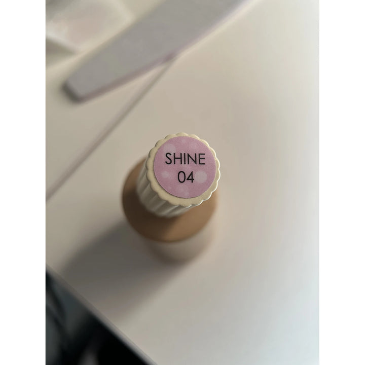 SHINE 04 gel nail polish bottle on white tabletop with manicure tool in background