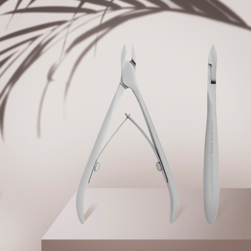 Stainless steel cuticle nipper and pusher for manicure on a minimal beige background