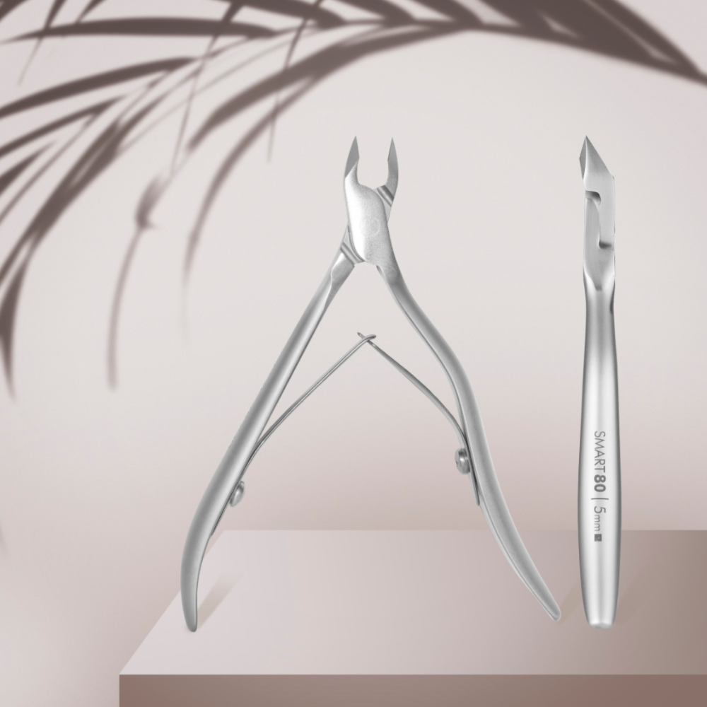 Stainless steel cuticle nippers and pusher for manicure on light background