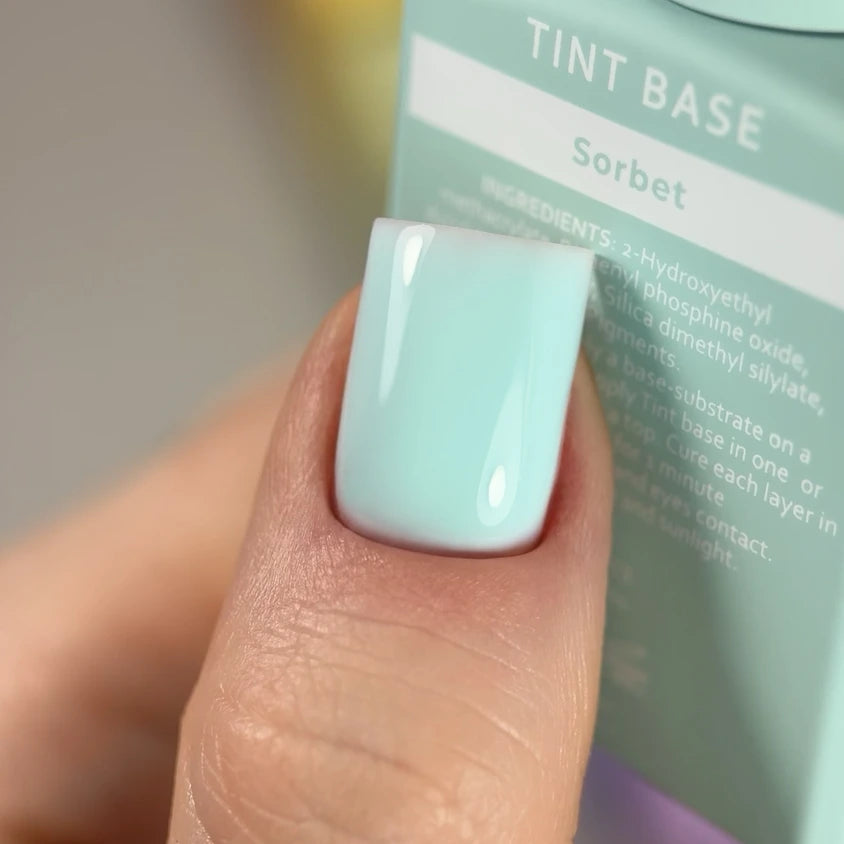 Close-up of a hand with a glossy pastel mint green gel nail polish manicure.