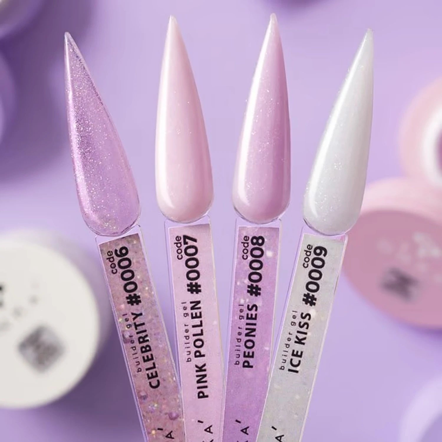 Four stiletto-shaped nail tips coated in glossy purple-toned nail polish shades, shown upright with product labels. The shades are labeled Celebrity, Pink Polen, Peonies, and Ice Kiss, in pastel pink, lavender glitter, light pink, and icy white.