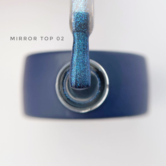 Blue glitter mirror top coat nail polish with brush applicator over open bottle