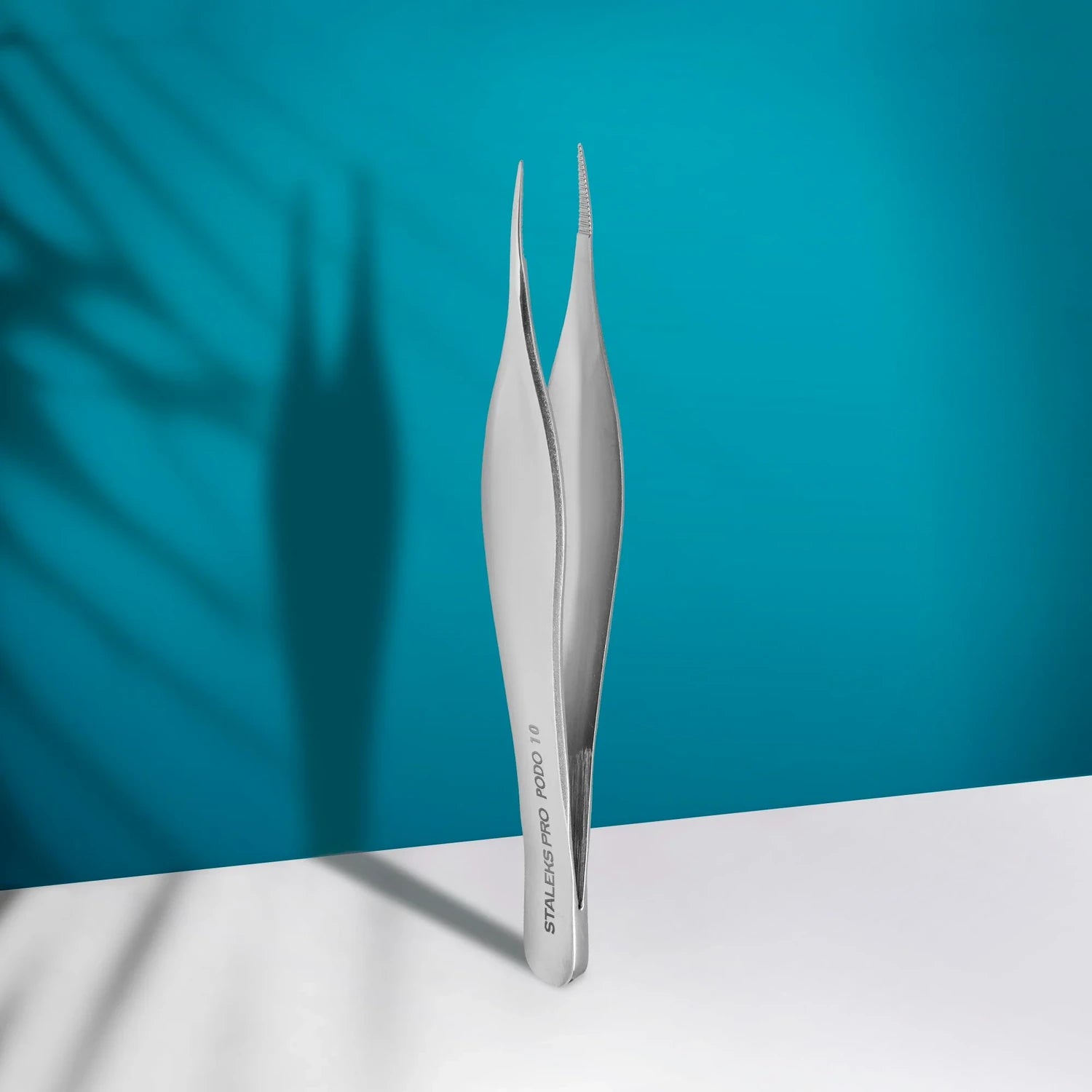 Professional stainless steel manicure tweezer on white surface with blue background