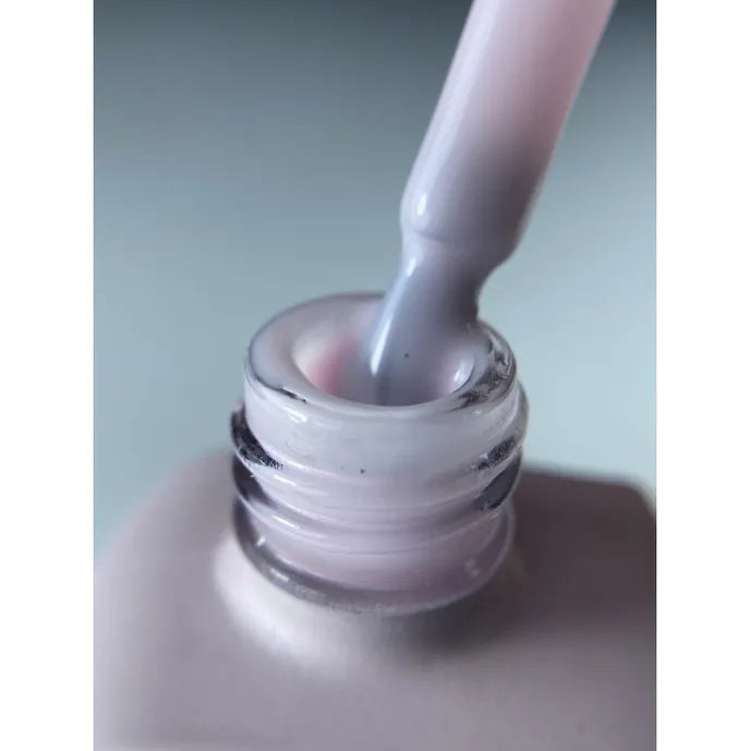 Close-up of a soft pink gel nail polish with brush applicator for manicure
